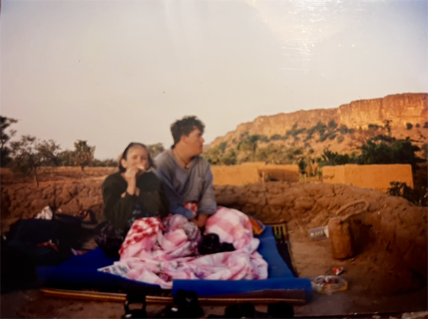 Mailloux and wife atop a Dogon hut, Bandiagara Escarpment in the background